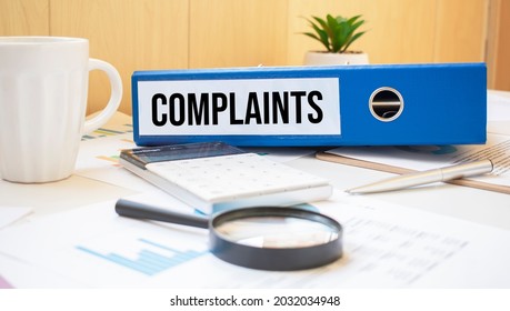 complaint words on labels with document binders with magnifier and coffee cup - Shutterstock ID 2032034948