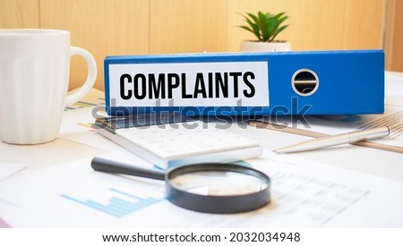 complaint words on labels with document binders with magnifier and coffee cup