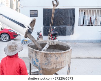 A complete construction sequence showing a cement mixer truck loading wet concrete into a crane-suspended bucket, which is then manually guided by workers to pour the foundation into steel formwork at a building site.