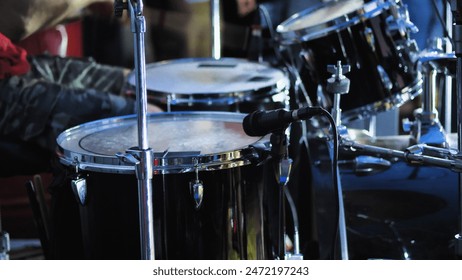 A complete drum kit for a single drummer including a variety of drums, cymbals and other percussion instruments. Black drum kit on stage - Powered by Shutterstock