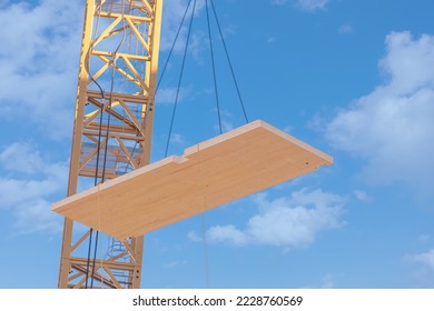 A complete laminated floor panel of a mass timber multi story green, sustainable, residential high rise apartment or office building construction project being lowered into place by a crane - Shutterstock ID 2228760569