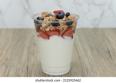 Complete meal contained in this cup of yogurt, blueberries, strawberries, and granola for plenty of protein and carbohydrates to eat.