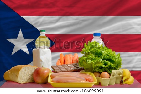 complete national flag of puerto rico covers whole frame, waved, crunched and very natural looking. In front plan are fundamental food ingredients for consumers, symbolizing consumerism an human needs