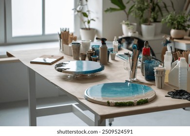 Completed epoxy resin art pieces on table in home loft studio. Round paintings with seaside motifs and working tools in creative space, craft, artistry, home based business, creativity for sale - Powered by Shutterstock