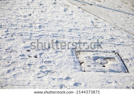 A completely snow covered sidewalk on a city housing project. Shoe tracks.