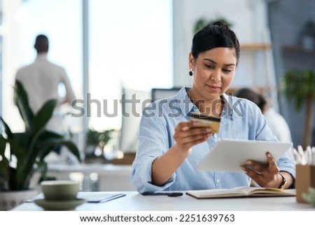 Completing business payments with ease. Shot of a young businesswoman using a digital tablet and credit card in an office.