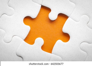 Completing final task, missing jigsaw puzzle pieces and business concept with a puzzle piece missing in the middle of the board on orange background and copy space