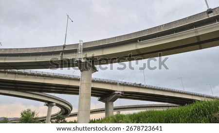 Complex elevated highway interchange with concrete bridges, urban transportation infrastructure under cloudy sky