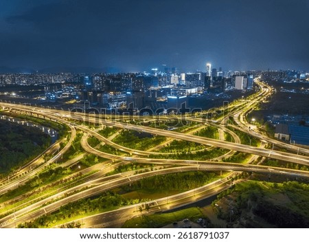 Complex highway interchange overpass system illuminated with traffic light trails in modern city at night.