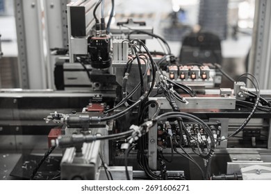 Complex industrial automation setup with densely packed black wiring, pneumatic connectors, and sensors integrated into a robotic processing line. Includes copy space