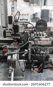 Complex industrial automation setup with densely packed black wiring, pneumatic connectors, and sensors integrated into a robotic processing line. Includes copy space