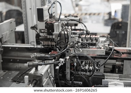 Complex industrial automation setup with densely packed black wiring, pneumatic connectors, and sensors integrated into a robotic processing line. Includes copy space