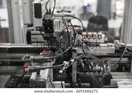 Complex industrial automation setup with densely packed black wiring, pneumatic connectors, and sensors integrated into a robotic processing line. Includes copy space