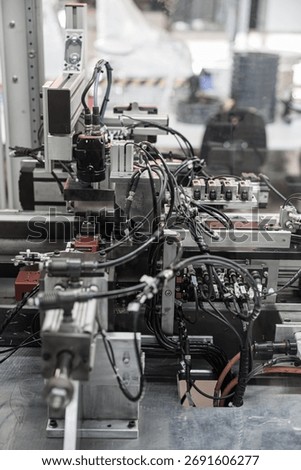 Complex industrial automation setup with densely packed black wiring, pneumatic connectors, and sensors integrated into a robotic processing line. Includes copy space