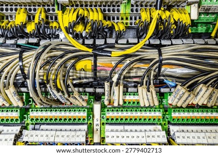Complex industrial electrical control panel with many labeled yellow wires and terminal blocks in a distribution board