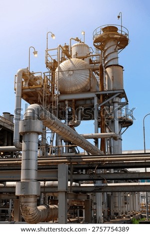 Complex industrial facility featuring deaerator tank and chimney of boiler at powerplant against a clear blue sky, representing manufacturing and energy production.