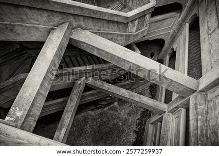a complex and intricate concrete structure with multiple intersecting beams and staircases, a maze-like appearance with various angles and plans