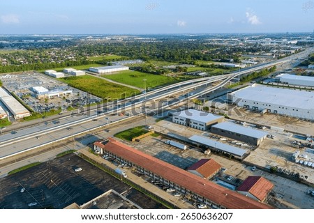 Complex multi level highway intersection with industrial warehouses, parking lots, surrounding suburban landscape in Houston, Harris County, Texas.