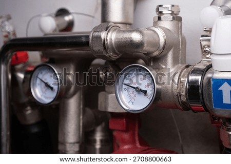 Complex residential heating manifold system with valves, gauges, and piping network.