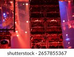 Complex stage lighting system with multiple fixtures and electronic equipment in atmospheric red lighting with haze effects