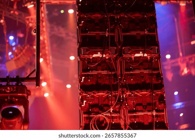 Complex stage lighting system with multiple fixtures and electronic equipment in atmospheric red lighting with haze effects