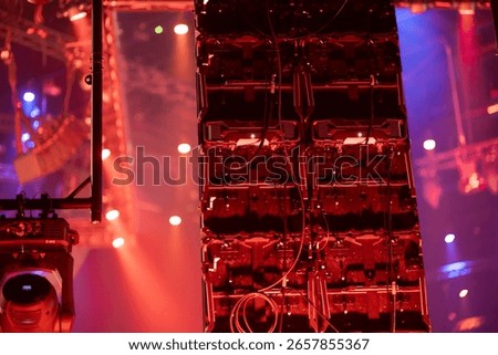 Complex stage lighting system with multiple fixtures and electronic equipment in atmospheric red lighting with haze effects