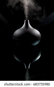 Complimentary Therapy. Modern Aromatherapy Aroma Diffuser Working. Dark Moody Image Backlit With Spotlights Against Black Background. Alternative Medicine In Question.