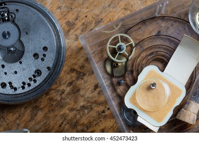 Components of a clock on a watchmakers workbench with a coiled spring and the mechanism in a close up overhead view - Powered by Shutterstock