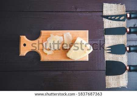 Composed Flat lay detail view of aged cheddar cheese with cheese knife set, over vintage brown wooden backdrop with copy space