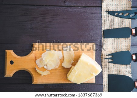 Composed Flat lay detail view of aged cheddar cheese with cheese knife set, over vintage brown wooden backdrop with copy space