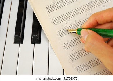 Composing Music And Writing On Old Music Score On A Black And White Piano Keyboard. For Concepts Like Music And Creativity.