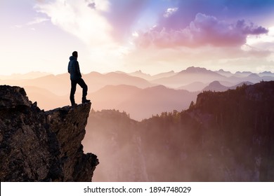 Composite. Adventurous Man Hiker With Hands Up on top of a Steep Rocky Cliff. Sunset or Sunrise. Landscape Taken from British Columbia, Canada. Concept: Adventure, Explore, Hike, Lifestyle - Powered by Shutterstock