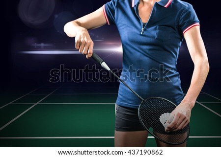 Composite image of badminton player holding a racket ready to serve against dark background