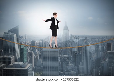 Composite image of businesswoman performing a balancing act against cityscape