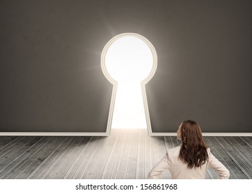 Composite image of businesswoman standing back to camera in room with keyhole shaped door - Shutterstock ID 156861968