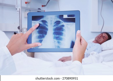 Composite Image Of Doctor Looking At Xray On Tablet