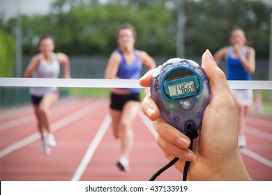 Composite image of a hand holding a timer against athletes racing towards finish line - Powered by Shutterstock