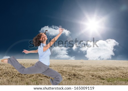 Composite image of happy classy businesswoman jumping while holding smartphone