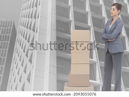 Composite image of stack of carboard boxes and caucasian businesswoman against tall buildings. business concept