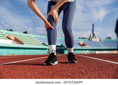 Composite image of a woman running in a track and field holding her sore knee due to arthritis and an x-ray bone - Powered by Shutterstock