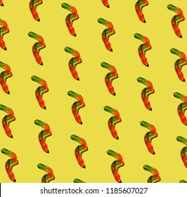 Composite pattern of worm-shaped gelatin candy against bright yellow background.
