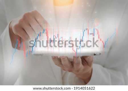 A composite photo of a woman's hand operating tablet PC and a stock chart