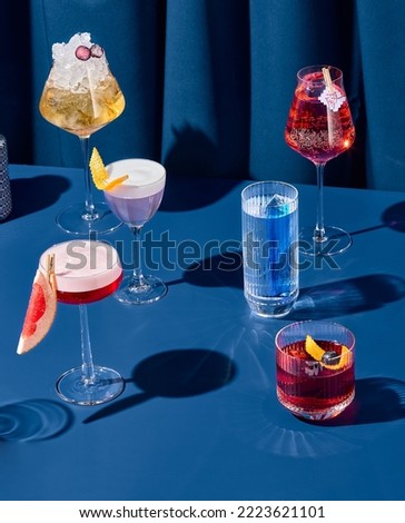 Composition with alcohol cocktails on coloured background with harsh shadows. Trendy concept cocktail menu. Set of cocktails on blue background. Bartender cocktails in minimal modern style