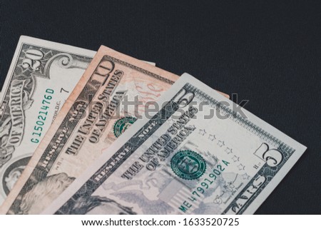 Composition of all US dollar notes stacked on a black background with space for copying.