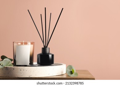 Composition with aromatic reed air freshener on wooden table near pink wall, space for text