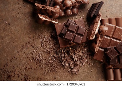 Composition of bars and pieces of different milk and dark chocolate, grated cocoa on a brown background top view close up - Shutterstock ID 1720343701