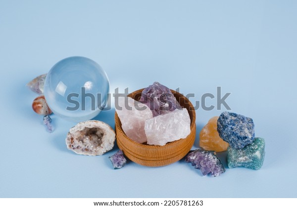 A composition of beautiful semi-precious\
stones, crystal ball and druze on a blue background. The concept of\
divination, magic rituals, predicting the future. Space for text,\
close-up.