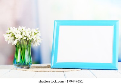 Composition With Beautiful Snowdrops In Vase, Photo In Frame On Wooden Table On Bright Background