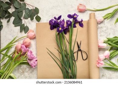Composition with beautiful spring flowers, scissors and wrapping paper on light background