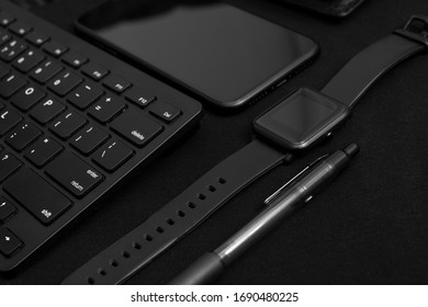 Composition with black pen, computer keyboard, smart watch, smartphone and leather wallet on dark black surface. Business concept. Business people items. Free space for text. Low key photo. 